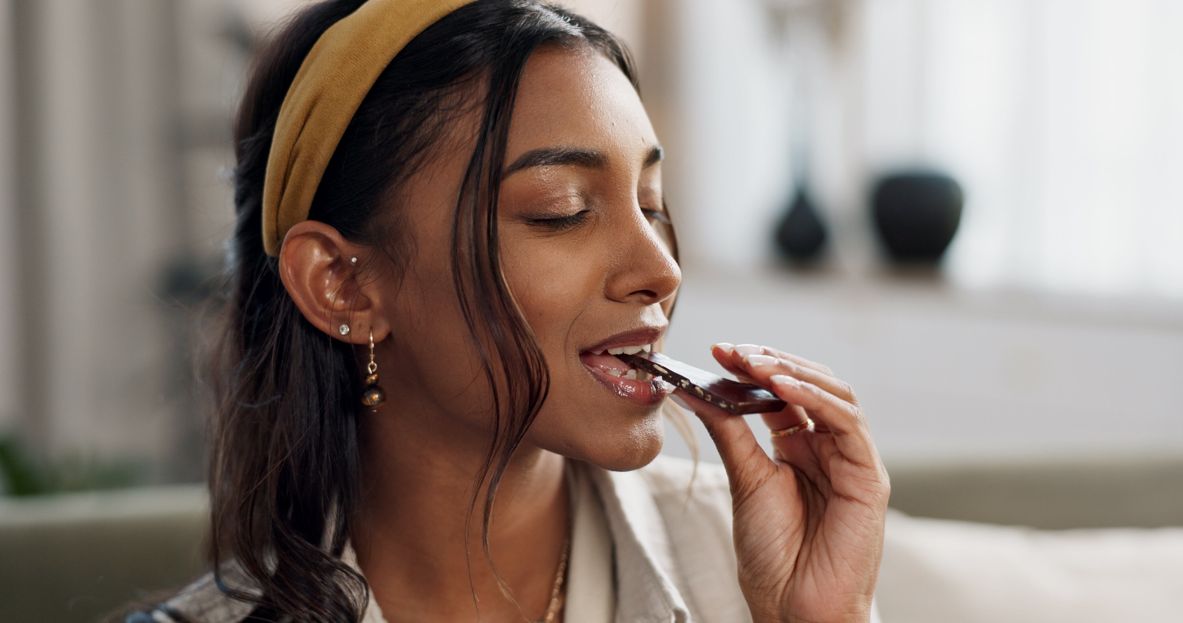 Home, relax and woman with chocolate bar, candy and eating with dessert, hungry or diabetes. Person, apartment or girl on a sofa, smile or sweet treats with a snack, nutrition or diet plan with cacao