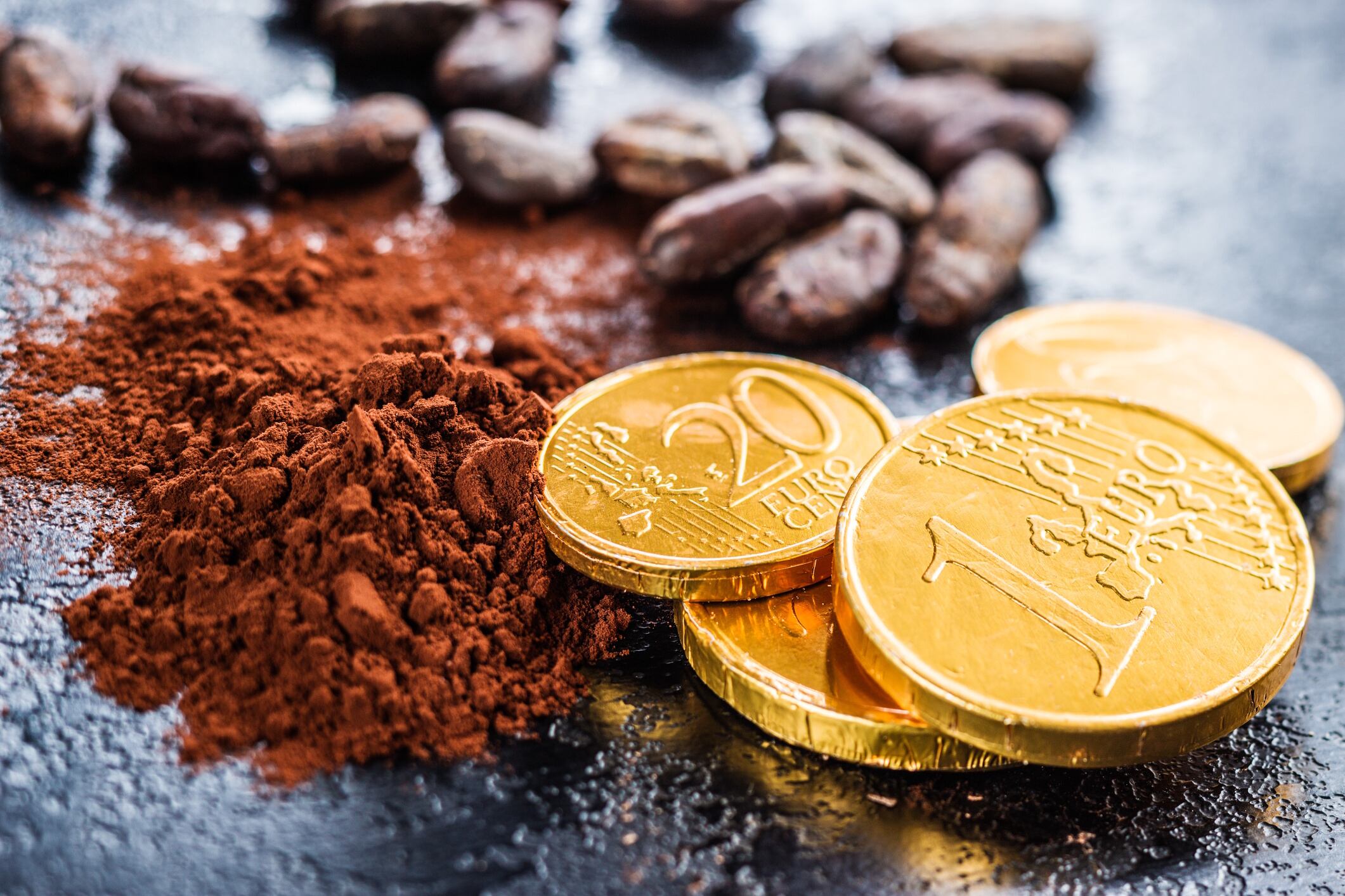 Dark cocoa powder, cocoa beans and chocolate euro coins jirkaejc GettyImages
