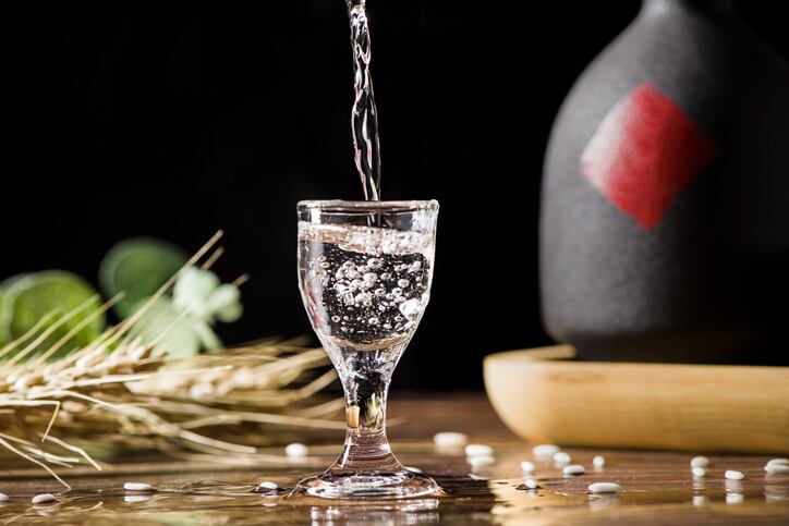chinese liquor spirits drink is poured into a glass from a bottle on wood background