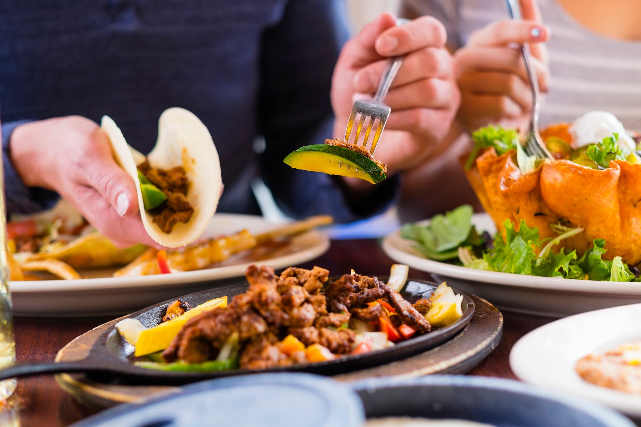 A young man eating a fajita at a restaurant table