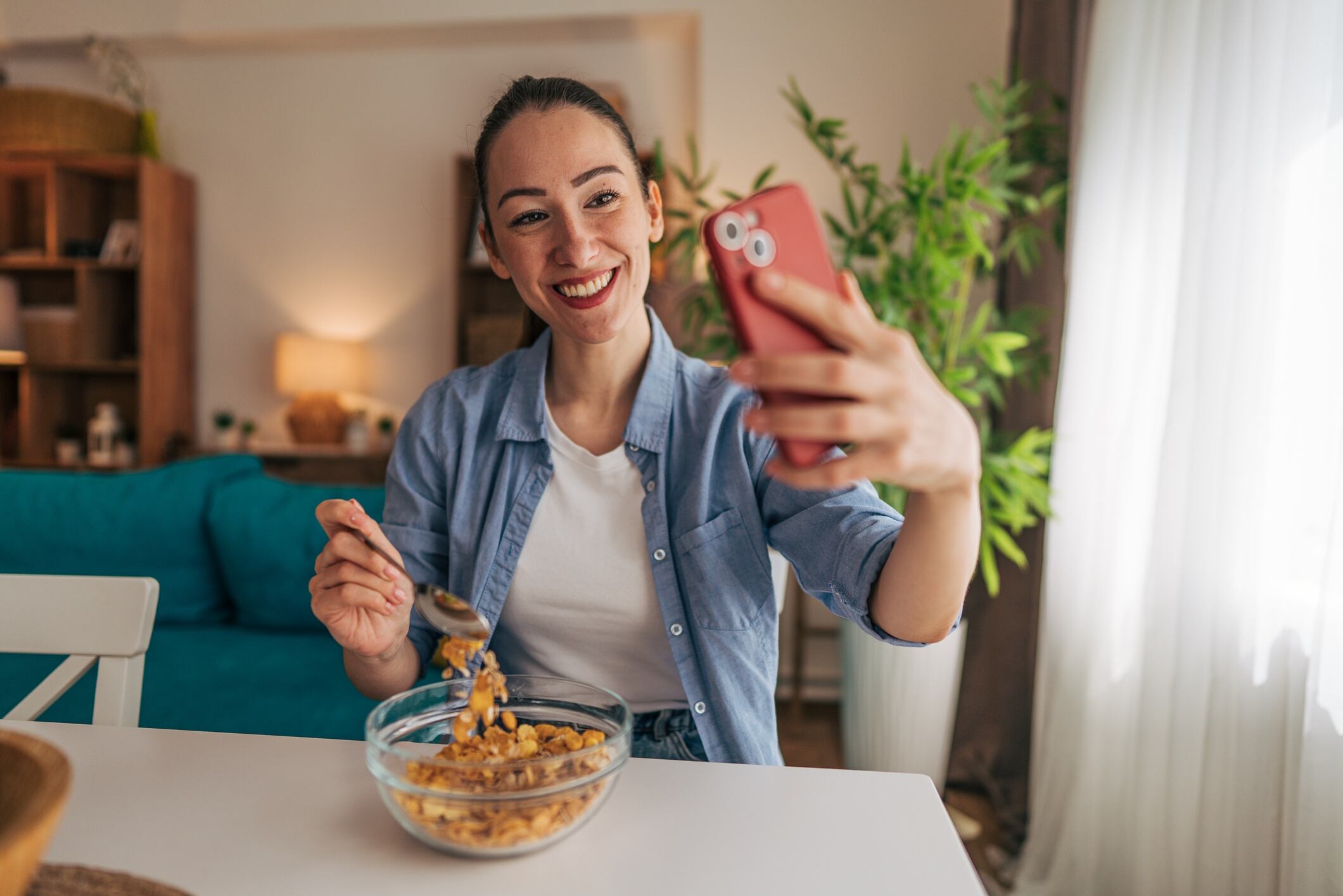 Young woman taking a selfie while eating breakfast