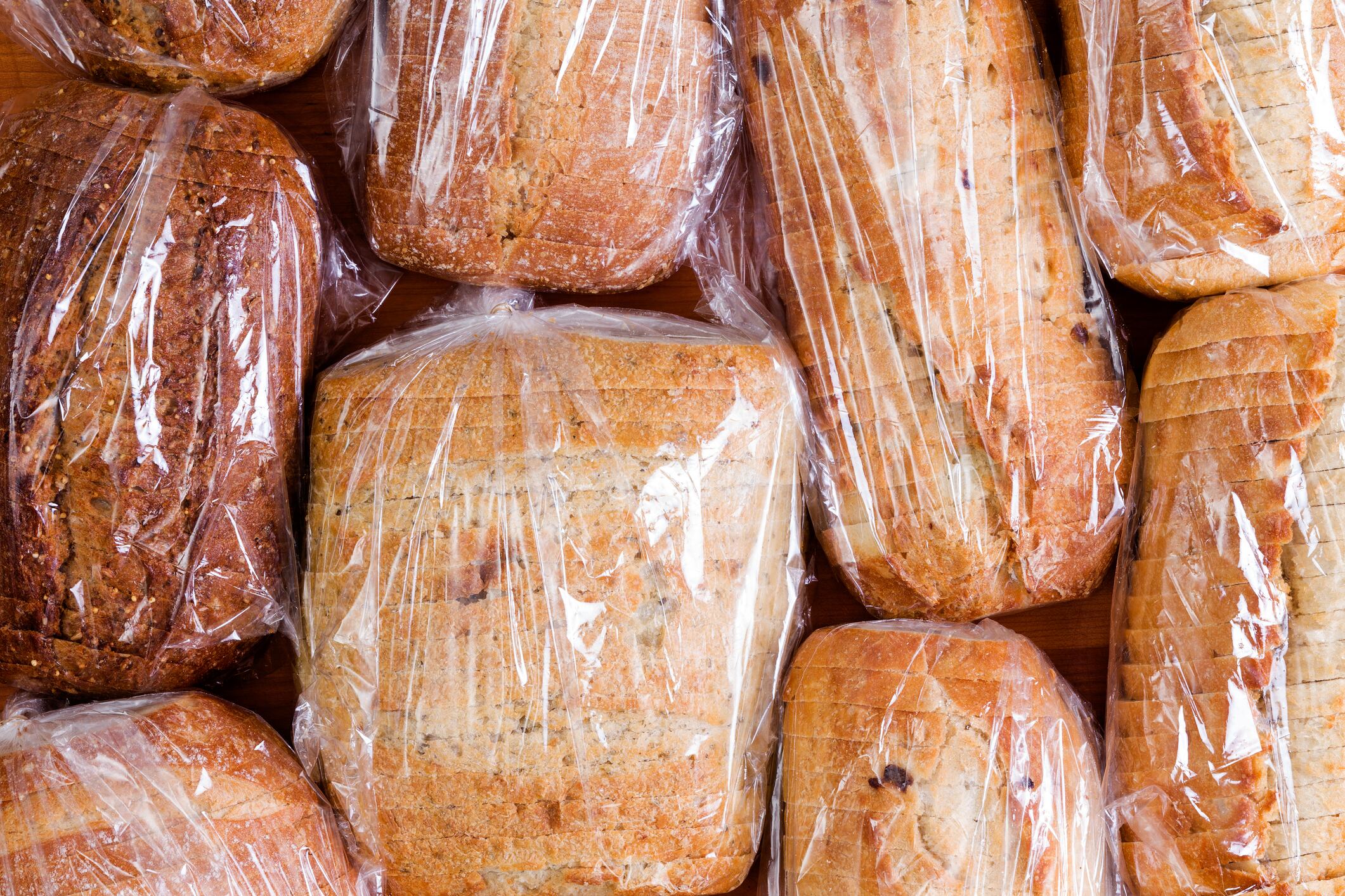 Assortment of different healthy white, wholegrain and wholewheat sliced loaves of fresh bread sealed in plastic bags ready to be distributed in a food drive, full frame overhead view.