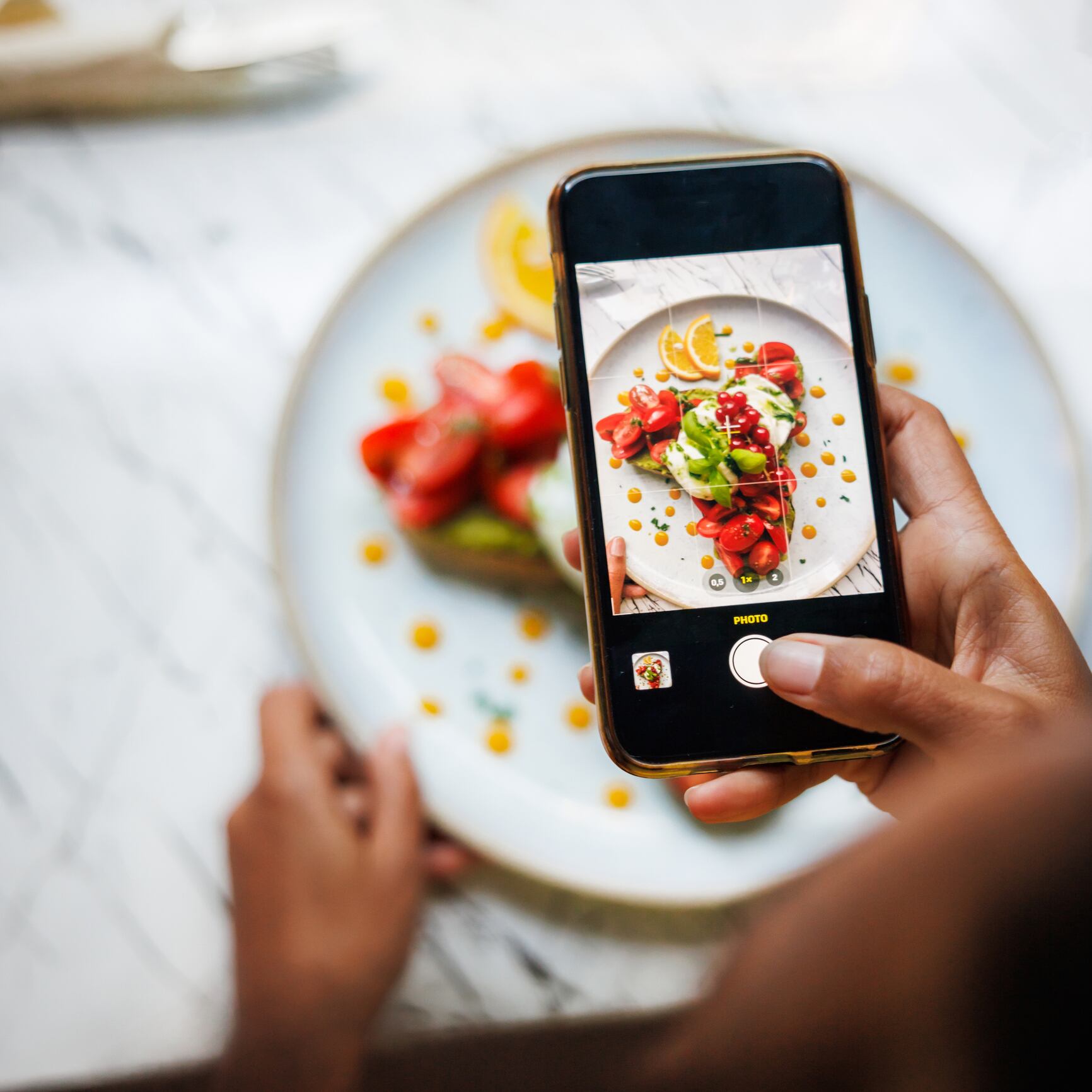EFSA told to speed up its novel food approval systems. Image: A person photographs a beautifully presented bruschetta on a ceramic plate with a smartphone, capturing the essence of food styling.