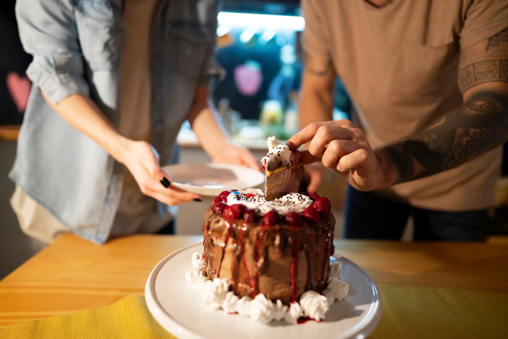 Man cutting a piece of cake - focus is on cake.