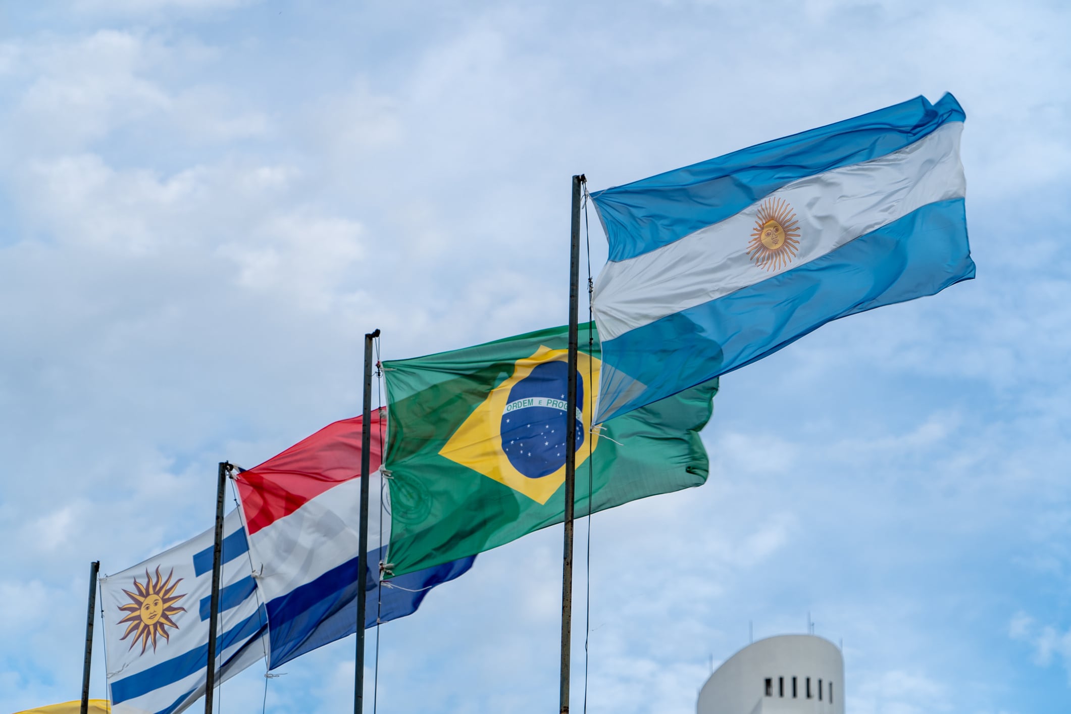 Mercosur flags flying high. Several flagpoles with Mercosur flags. Latin American flags. South American flags Brazil Argentina Paraguay Uruguay