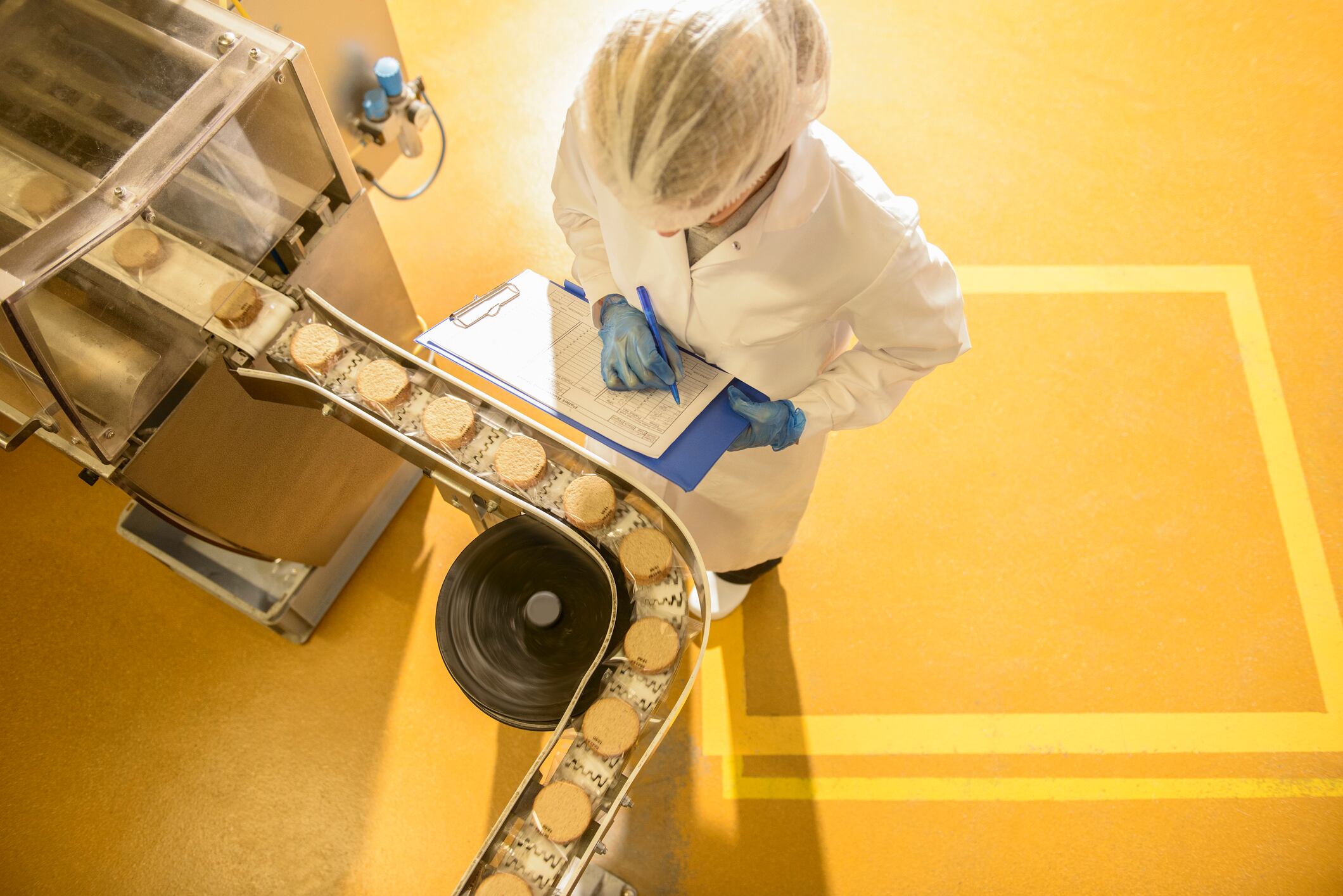 EFSA food and drink threats on the up. Image: Overhead view of worker inspecting biscuits on production line in food factory