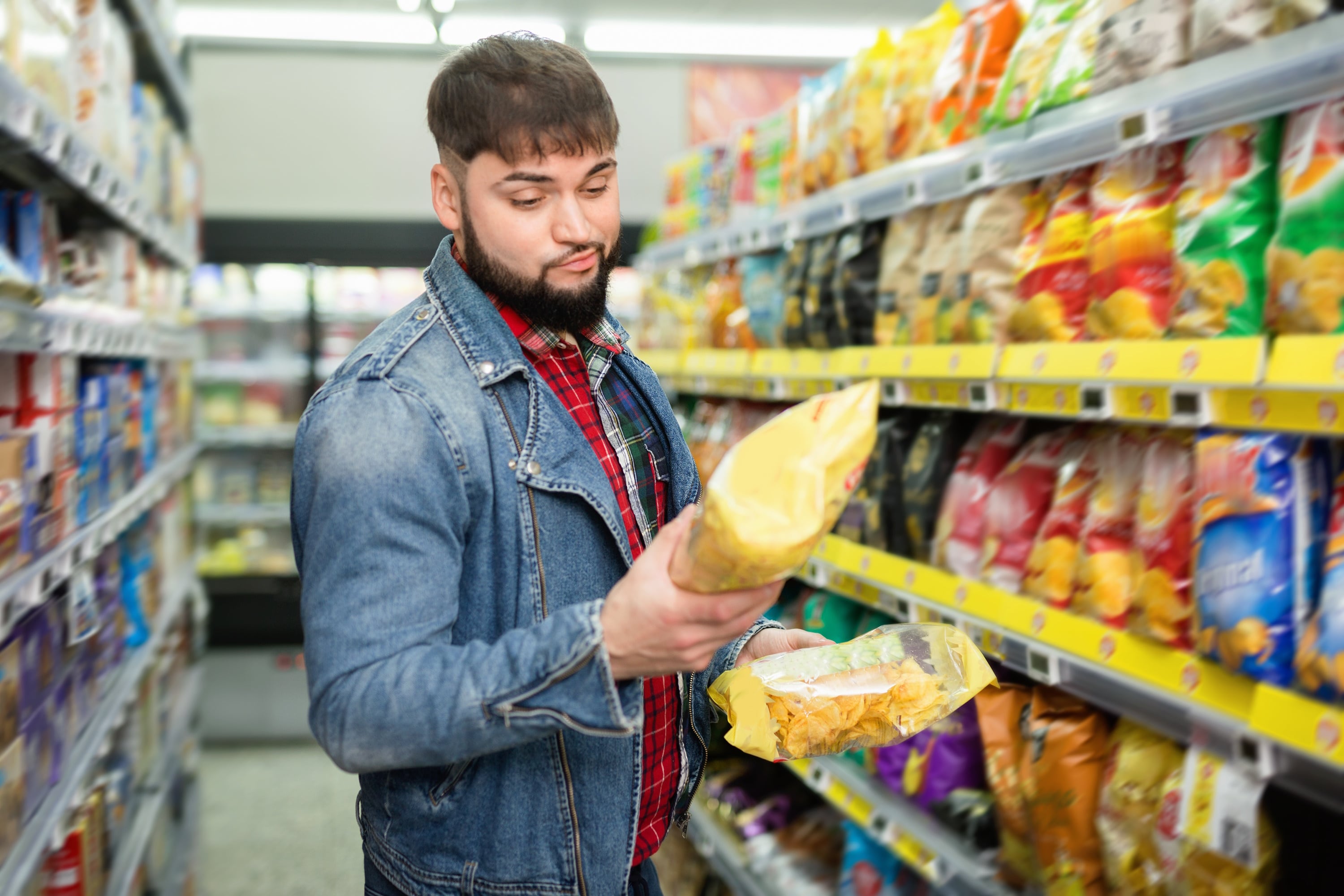 Bearded man looking at front of pack of chips