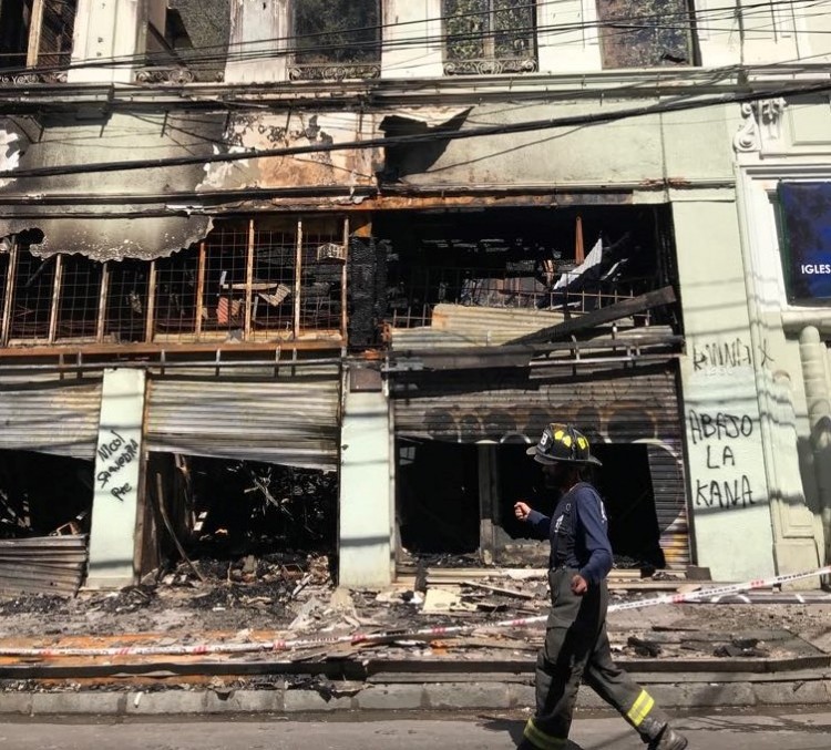 A firefighter walks past a shop damaged by fire in Valparaiso. Photo: Niamh Michail